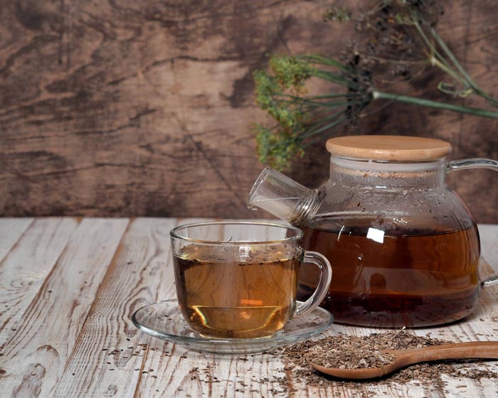 Glass teapot and cup of tea on a wooden surface with a wooden background