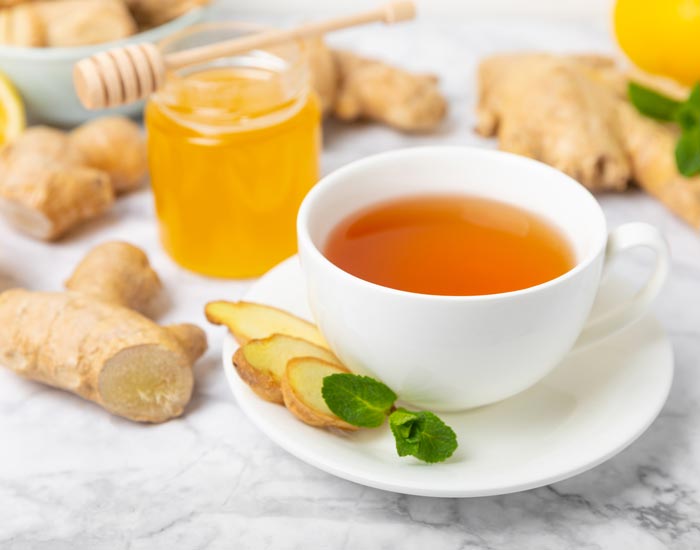 Tea cup with ginger slices, lemon, ginger, and honey on a marble surface
