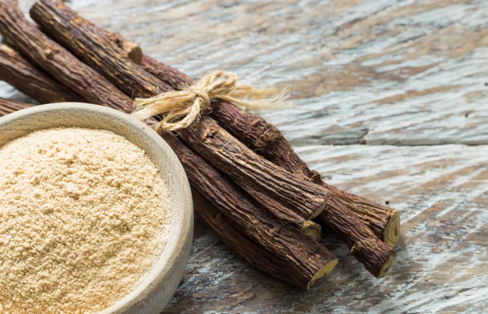 Licorice root and ground licorice powder on a wooden surface
