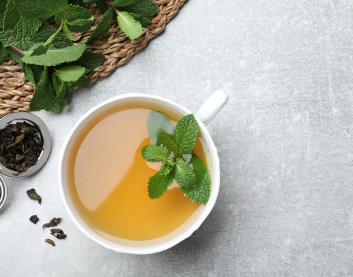 Tea cup with mint leaves on a light gray surface