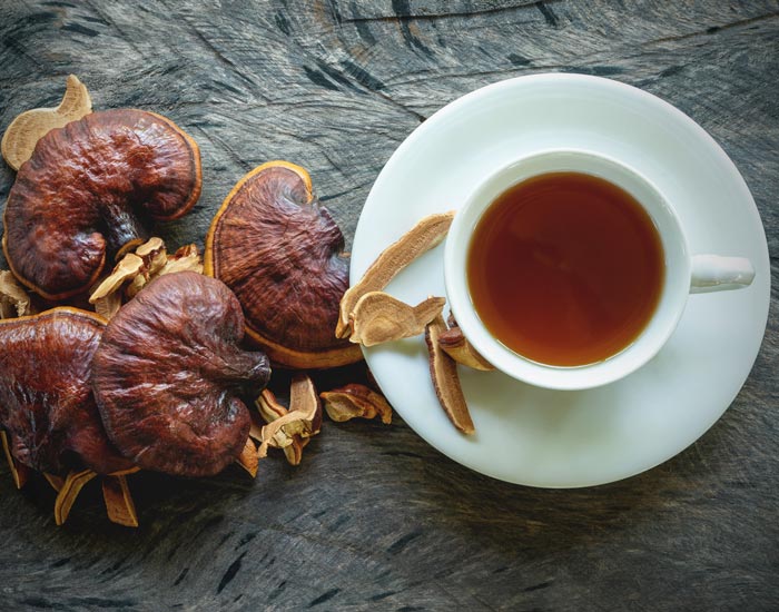 Dried herbs and a cup of reishi  tea on a wooden surface