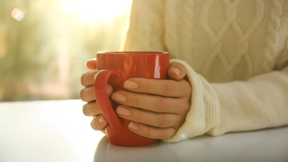 Person holding a red mug with a blurred background